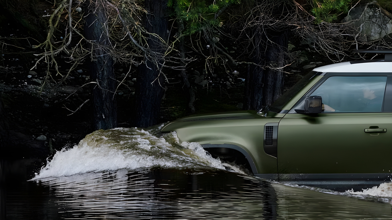 Defender 130 wading through water during an off-road river crossing.