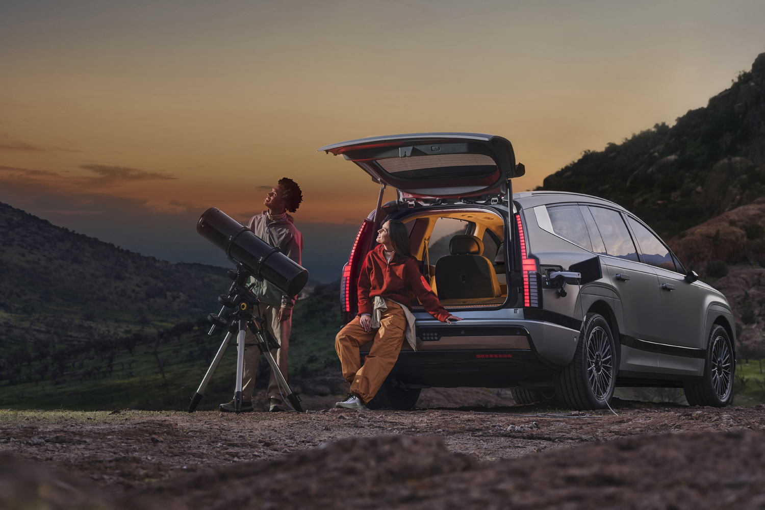 All-new IONIQ 9 at night with people stargazing and sitting in boot