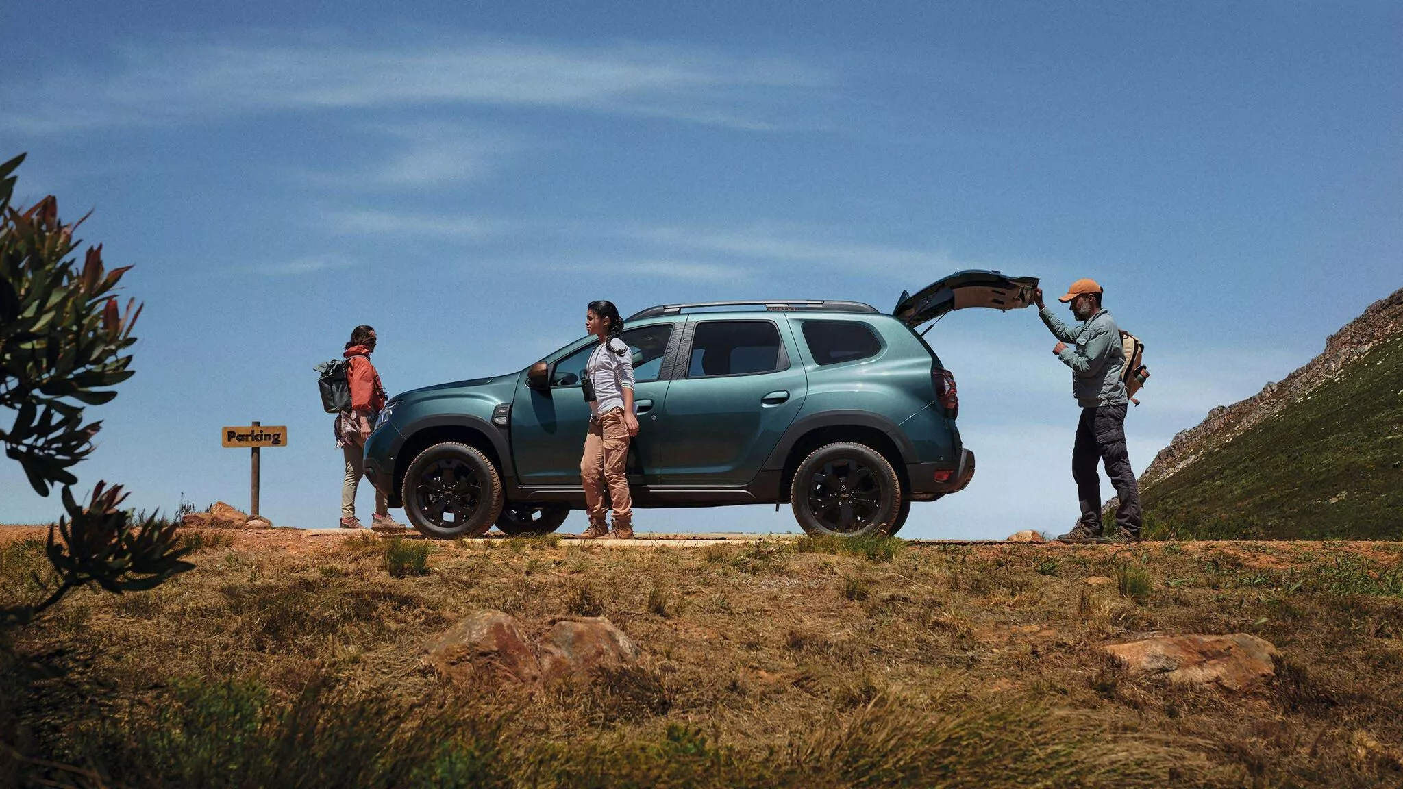 Blue Dacia Duster parked on top of hill with boot open