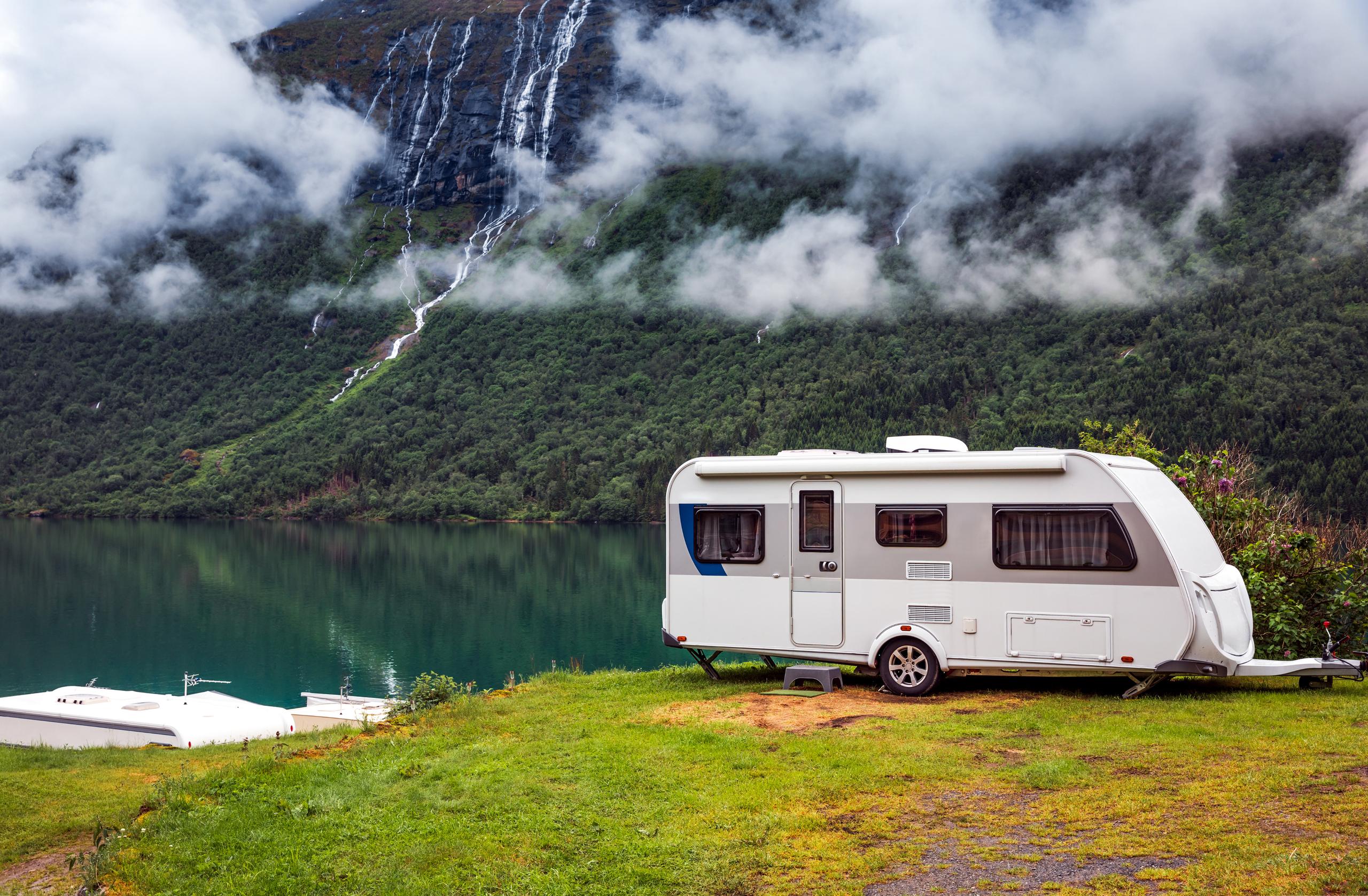 Camper trailer driving parked in a scenic outdoor environment.