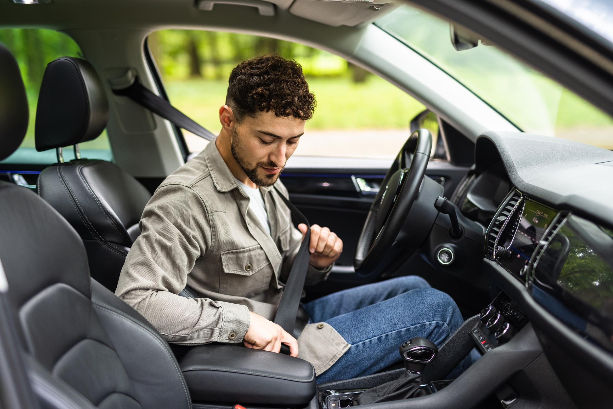 Man in car putting seat belt on