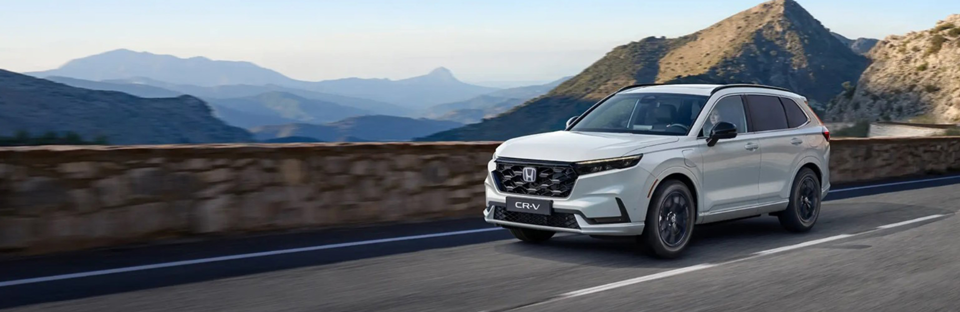 White honda crv driving fast on a mountain road.