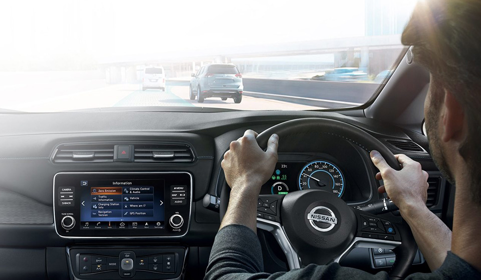 A man behind the wheel of a Nissan car, driving along a motorway.