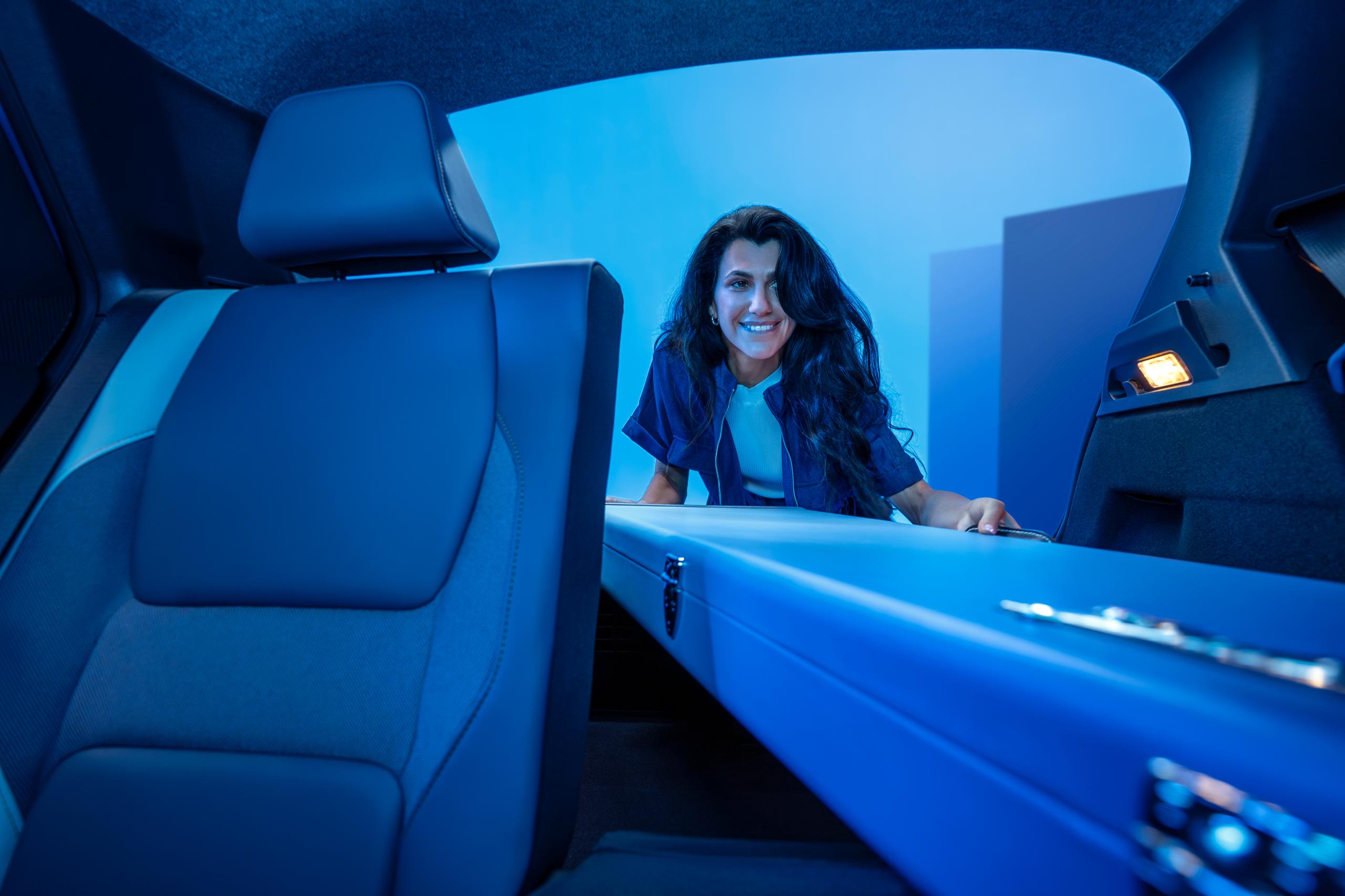 woman putting something in the boot of a blue car