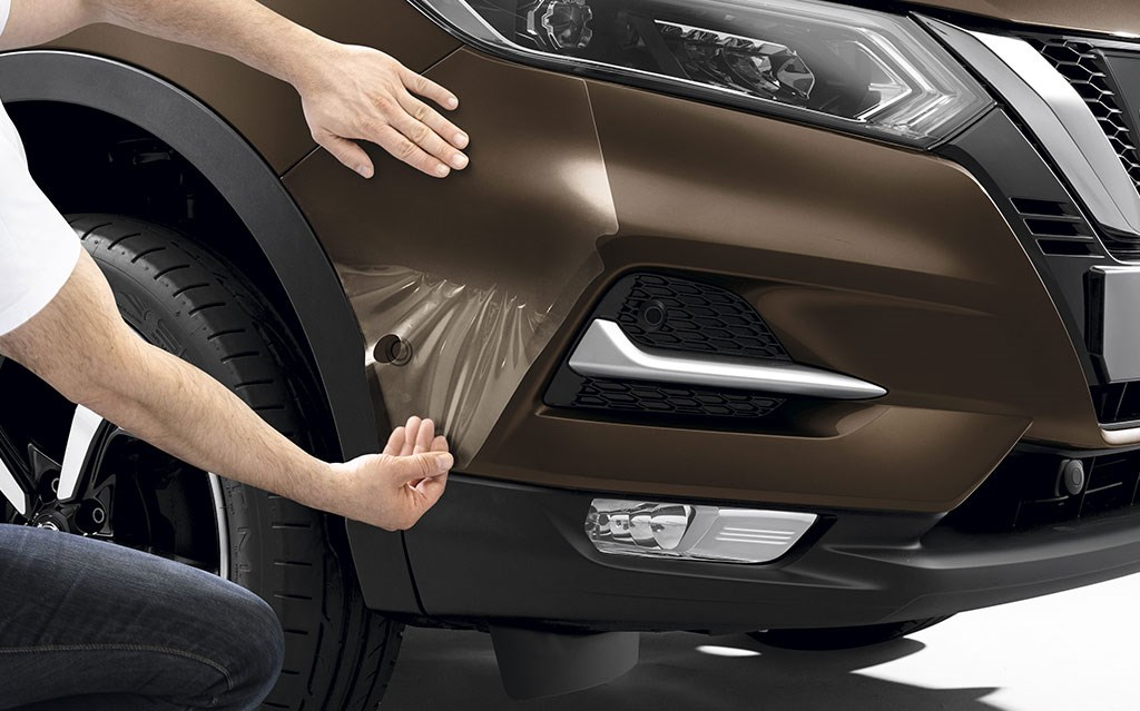 Man re-wrapping a gold nissan car