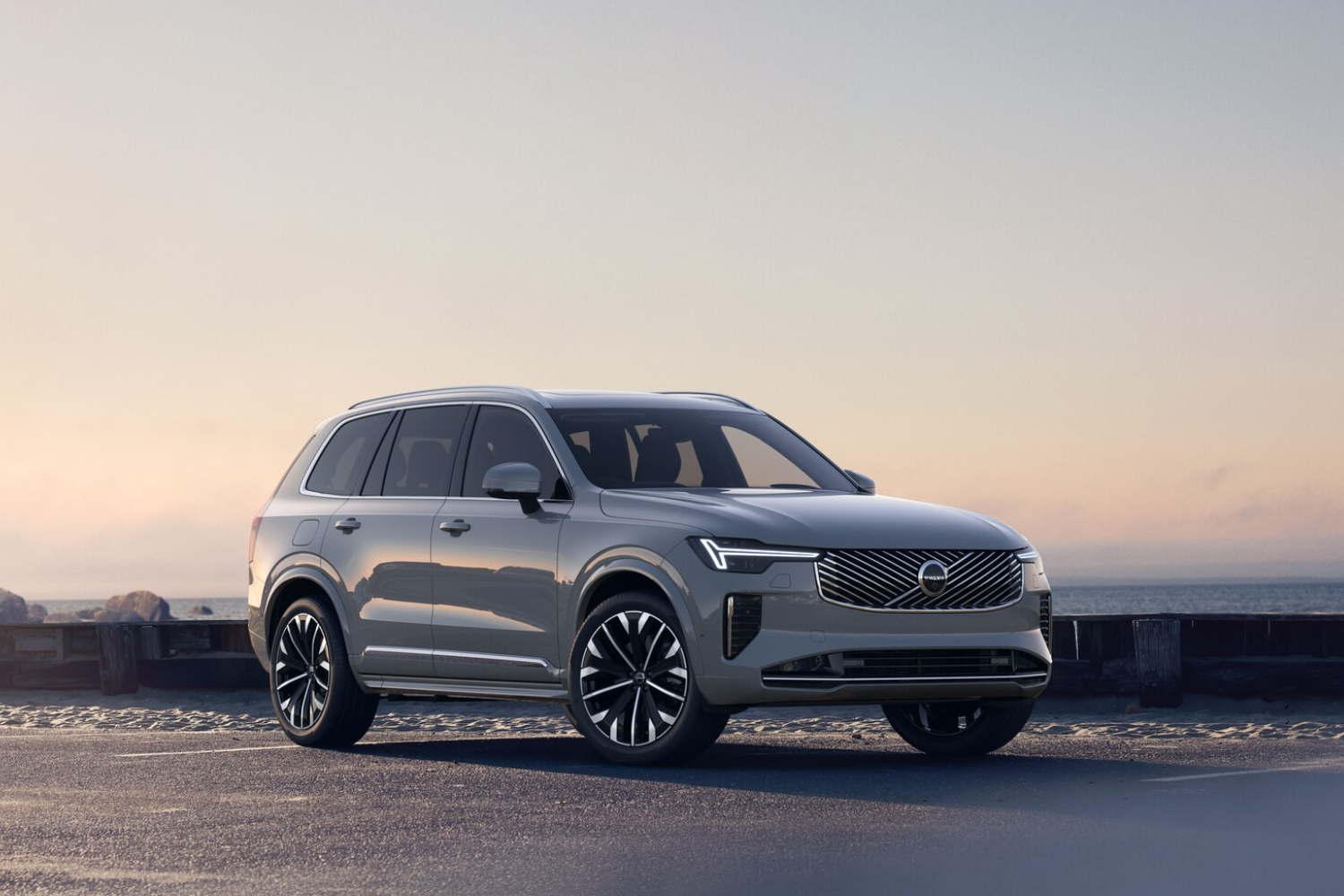 Silver Volvo SUV parked by the coast at sunset.