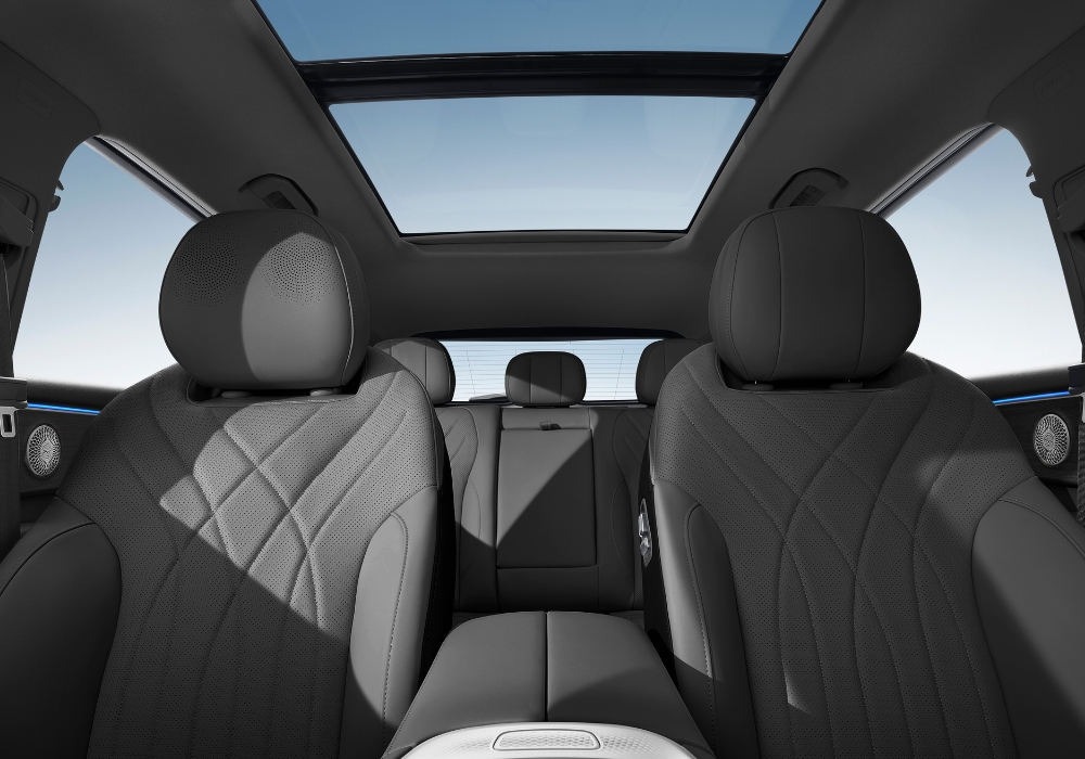 Rear passenger area of the OMODA 9 highlighting leather seats, stitching details, and the expansive glass roof.