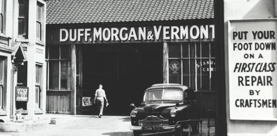 Black and white historic photo of the Duff Morgan & Vermont garage with an old car parked outside.