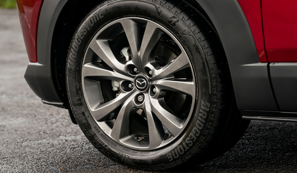 Rear wheel of a new mazda cx-30 with a silver hub cap.