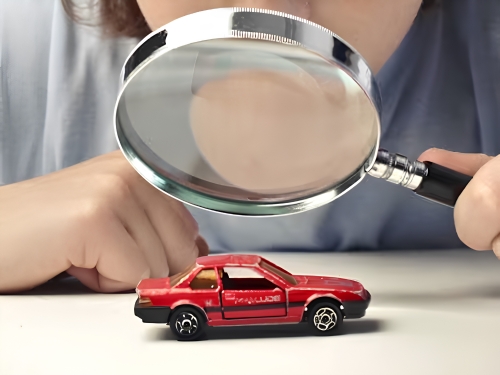 Magnifying glass inspecting a model car to represent a detailed vehicle inspection.
