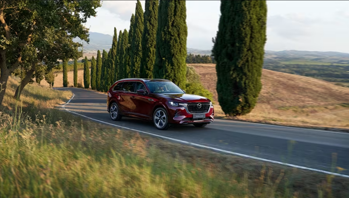 Cx-80 in dark red driving on a country road