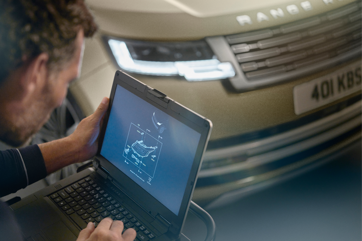 Range Rover technician carrying out vehicle diagnostics using laptop in workshop.