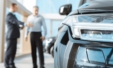 Close up of car headlight with 2 men stood next to it