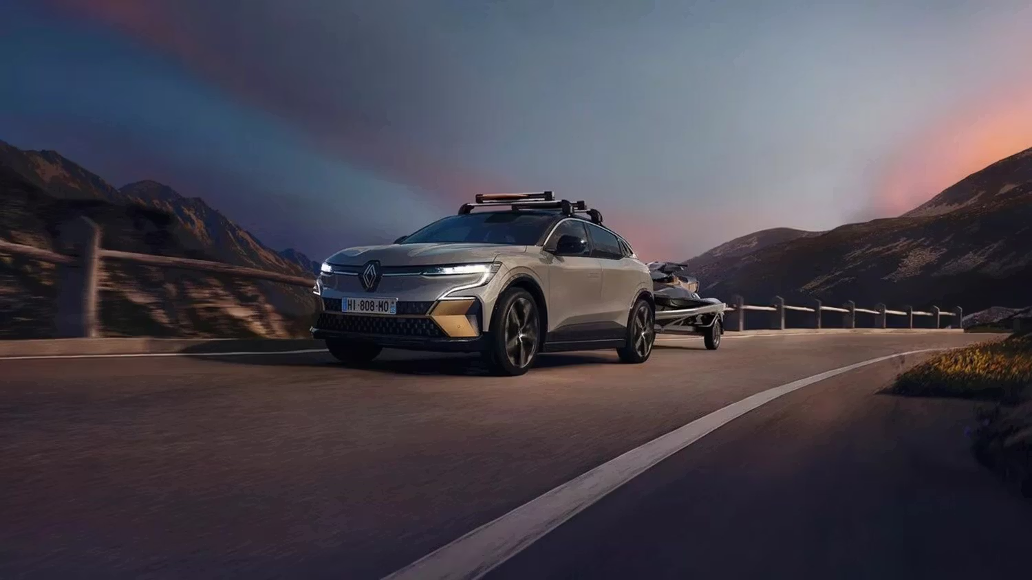 Renault vehicle towing a trailer on a mountain road at sunset.