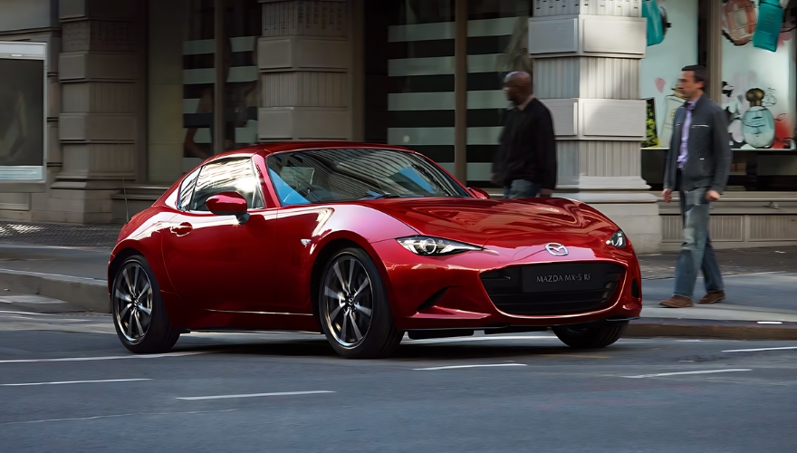 Red Mazda MX-5 RF driving in an urban setting