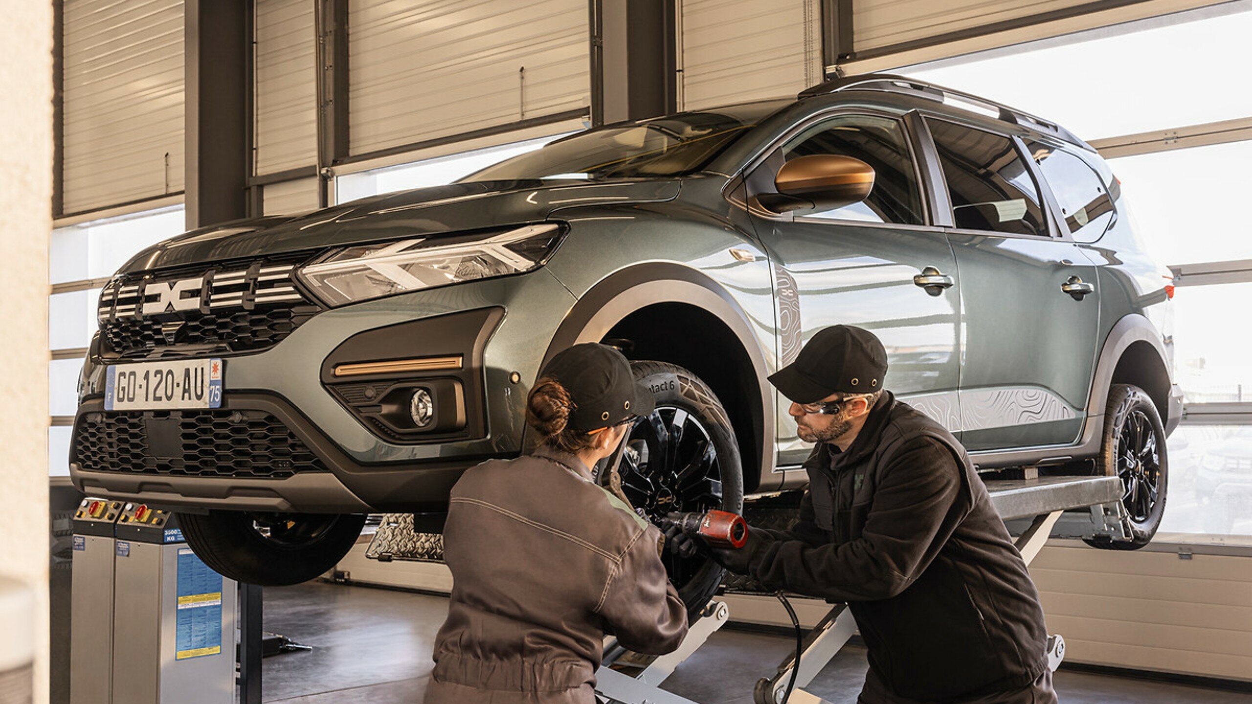 Mechanics working on a Dacia car during servicing.
