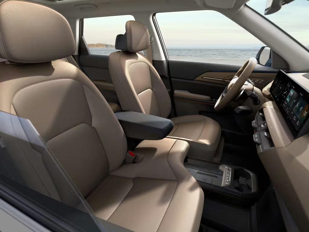 Side cutaway view of the Kia EV5 interior, showcasing spacious beige leather seating, modern dashboard with floating touchscreen display and refined centre console design.