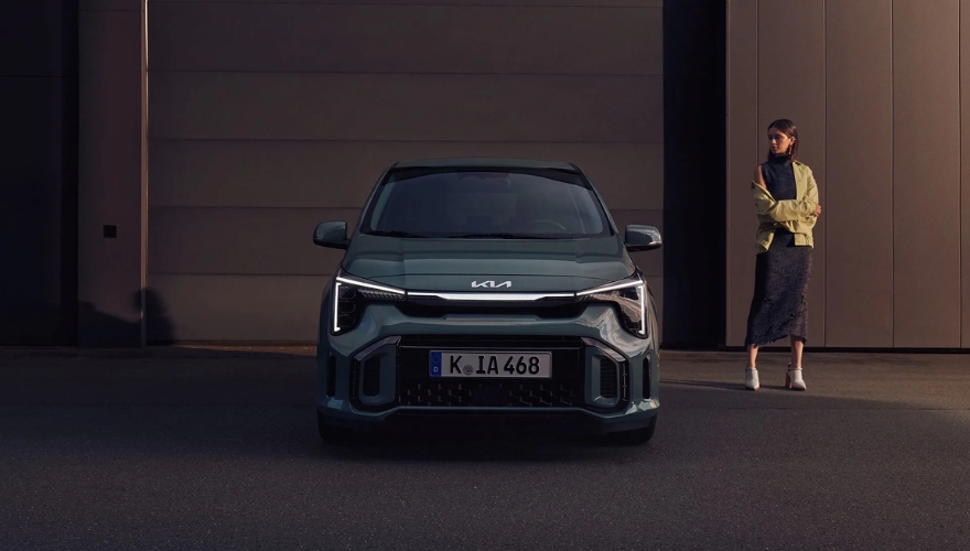 Kia Picanto in green parked outside a modern building with a person standing nearby