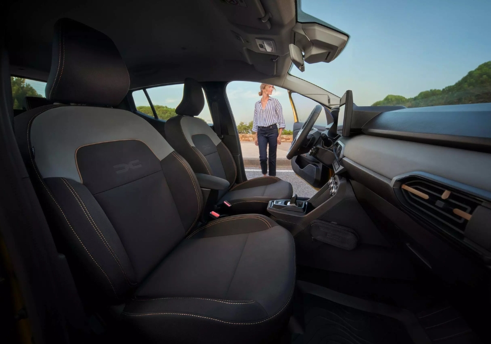 Dacia Sandero Stepway interior front seats with door open, highlighting upholstery detail and cabin space.