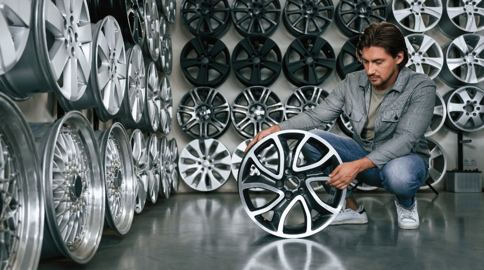 man looking at an alloy wheel in a store