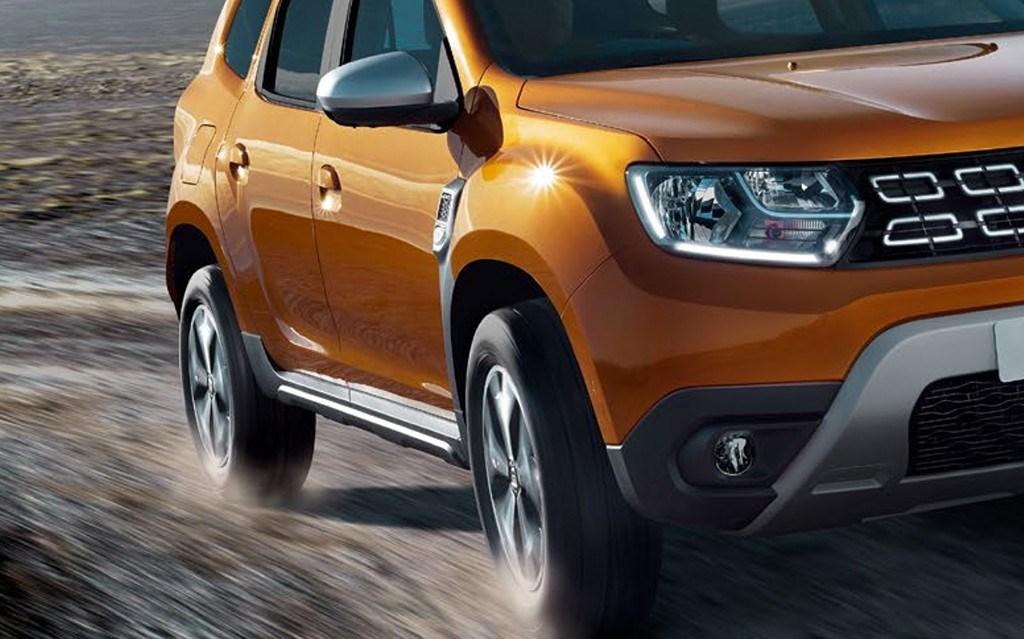 Close up of orange Dacia Duster driving on dirt road