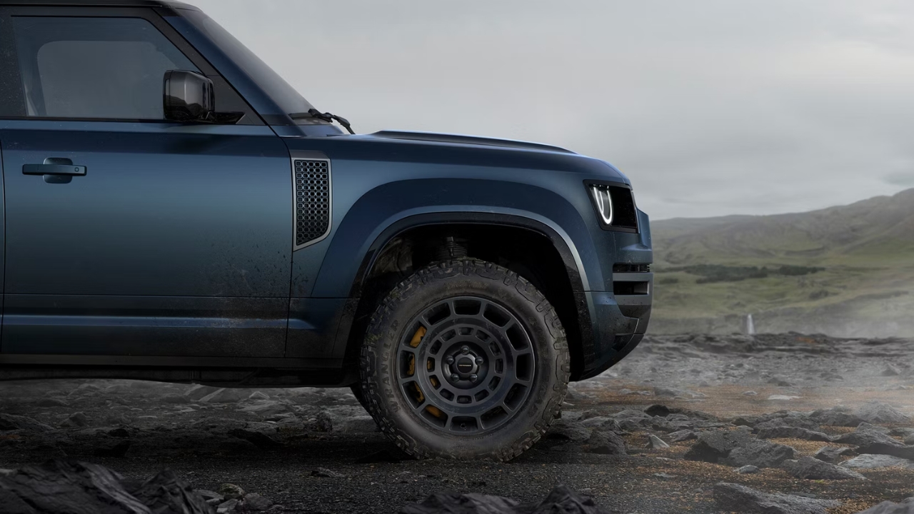 Close-up of the Land Rover Defender OCTA front wheel and off-road tyre on rocky terrain.