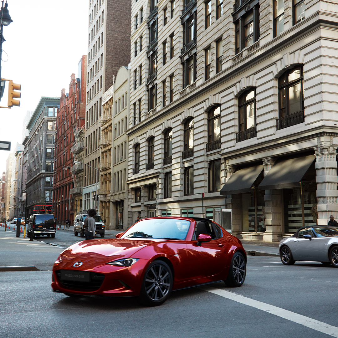 Red mazda driving through city streets