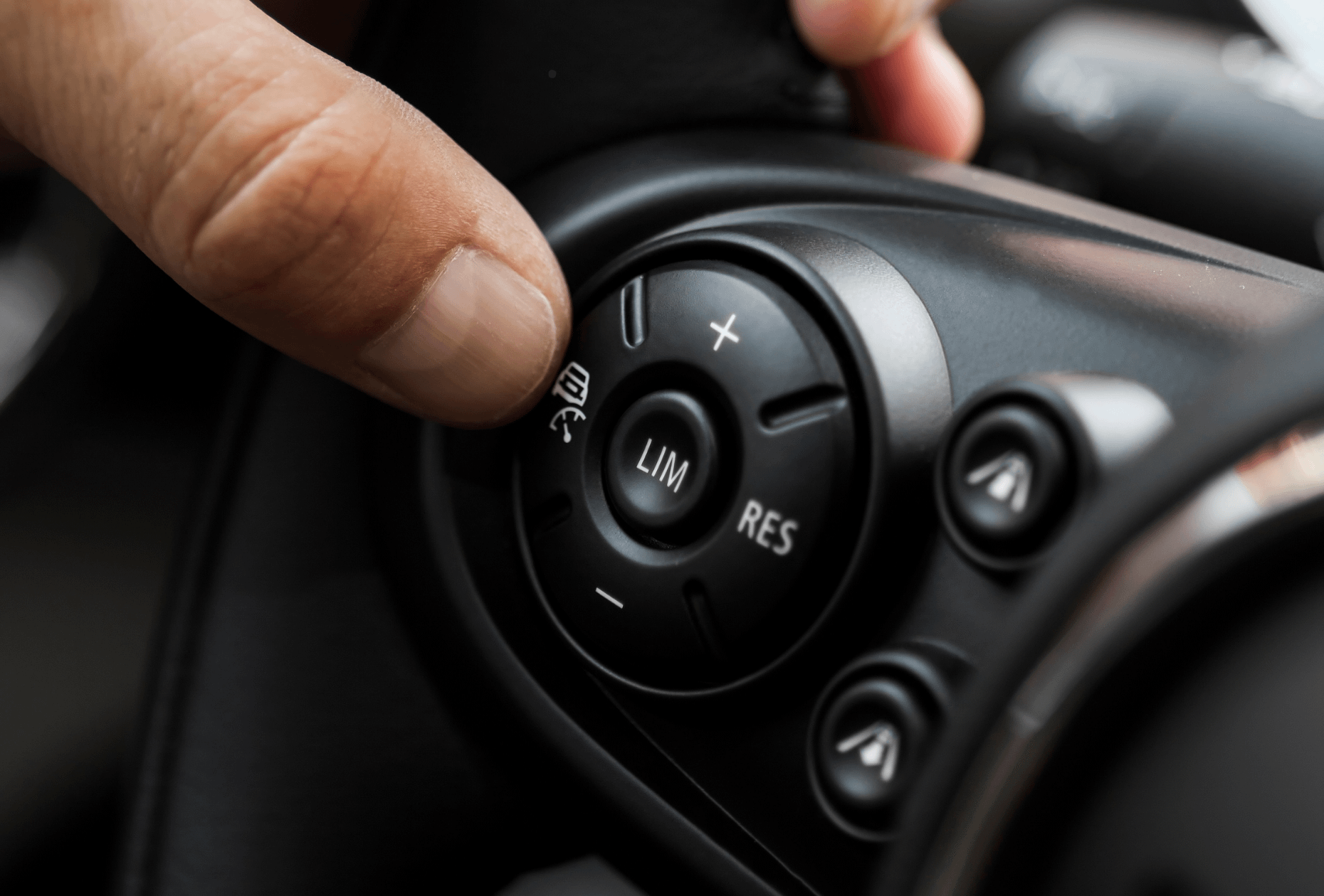 Thumb with on steering wheel about to press cruise control (adaptive) (intelligent) button