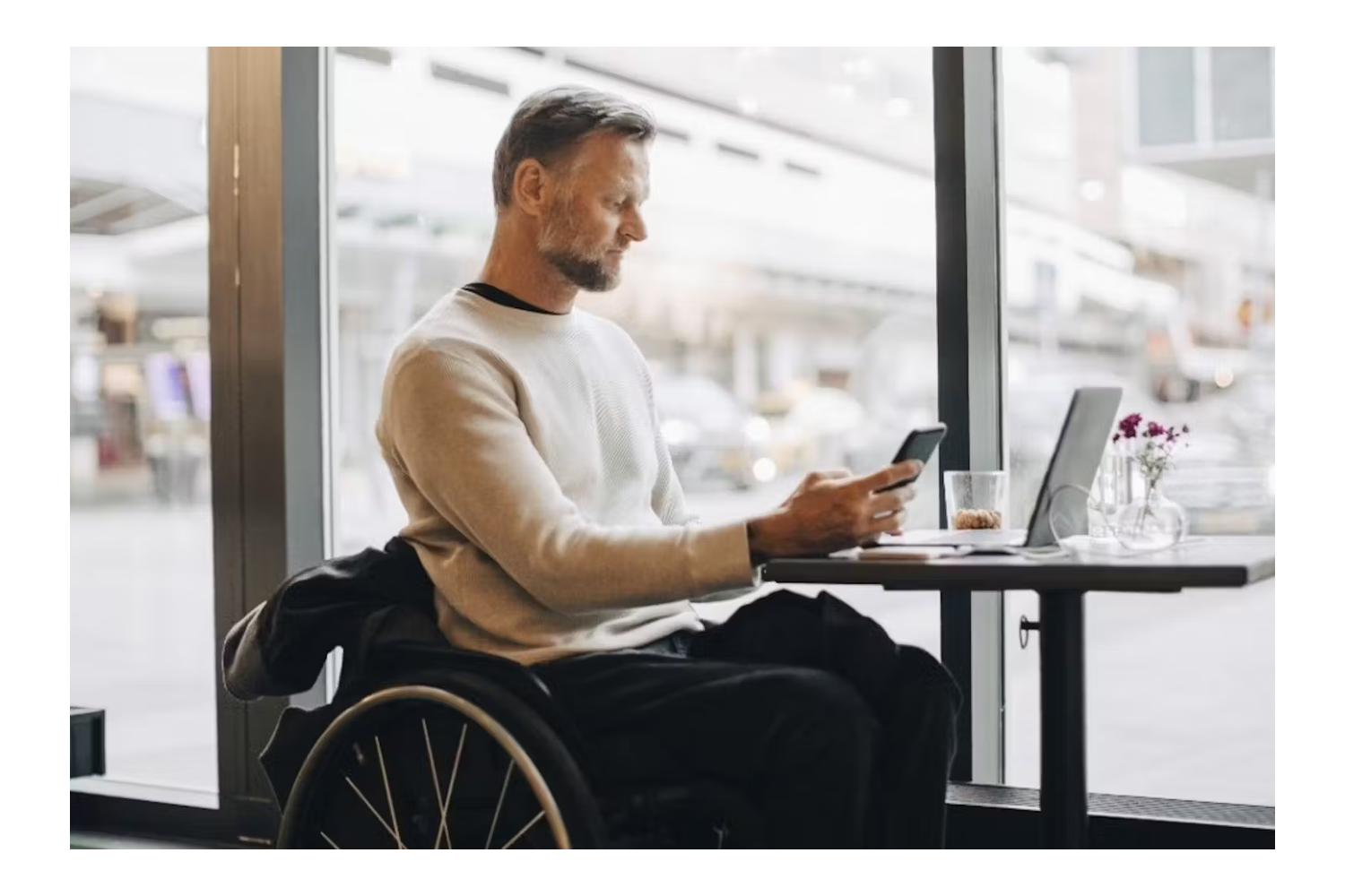 man in a wheelchair sat at a desk on his phone