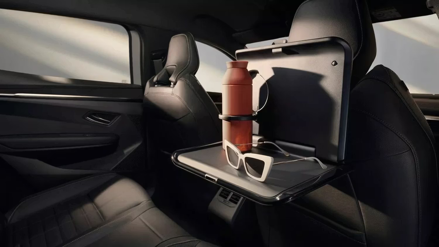 Renault vehicle rear seat with fold-down tray table holding a bottle and sunglasses.