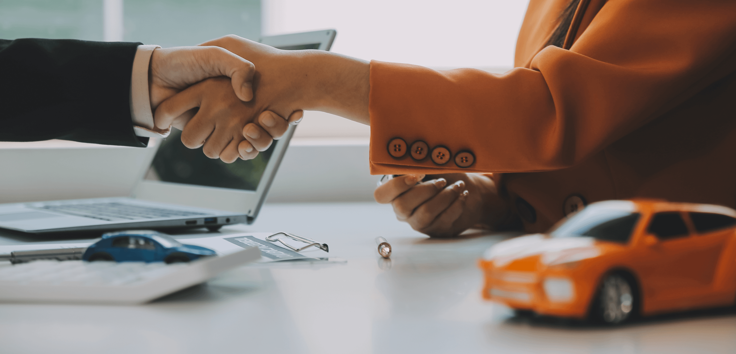 People shaking hands over a desk.