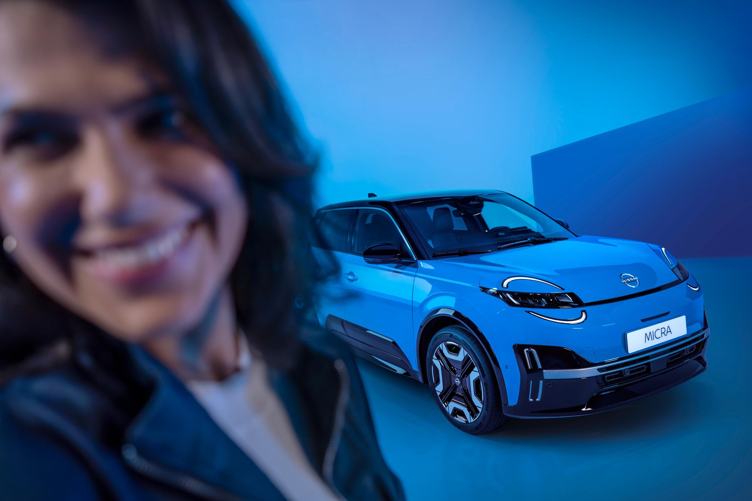 woman smiling in front of a blue car