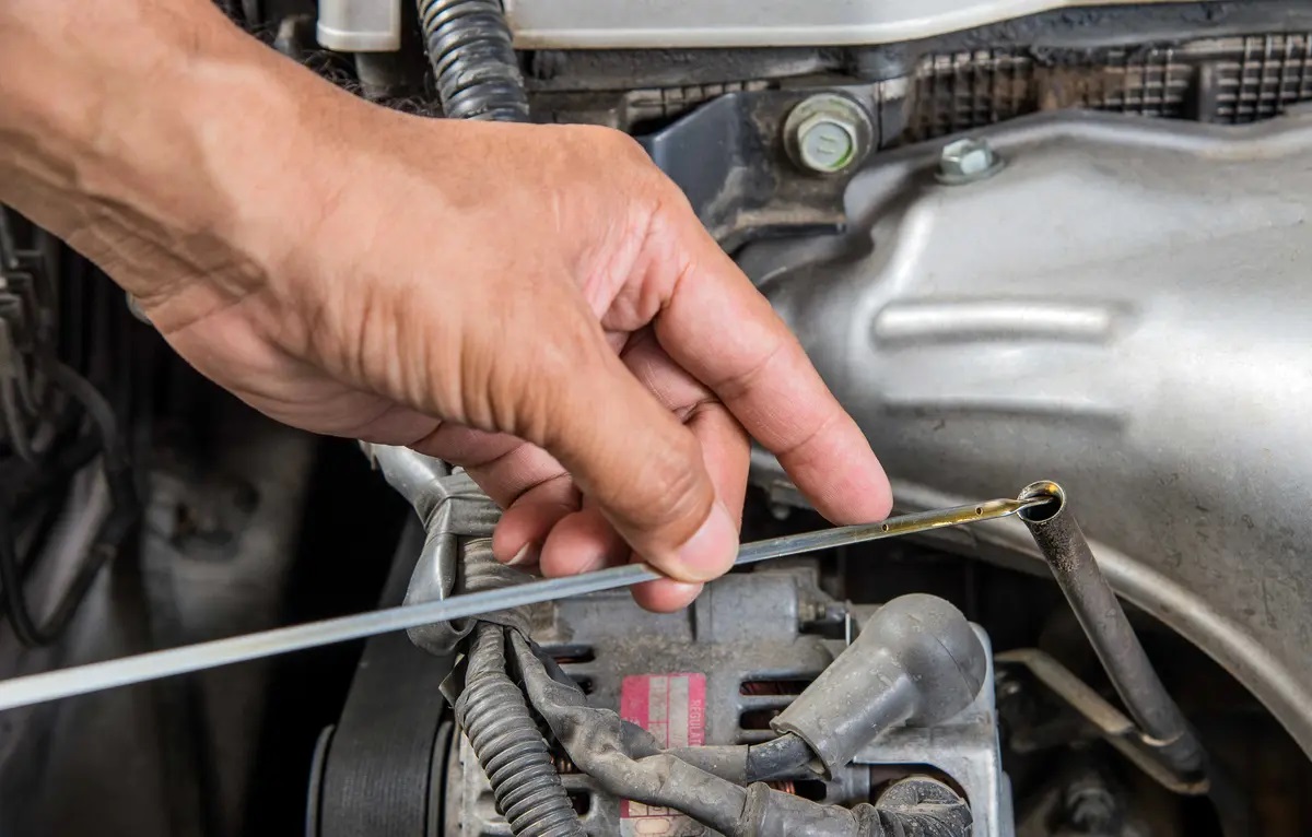Mechanic using dip stick to check car oil levels