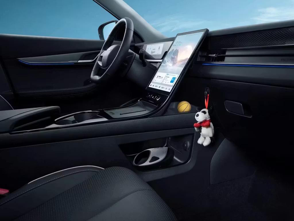 Interior view of the Jaecoo E5 showcasing the minimalist dashboard design, large portrait-oriented central touchscreen, black leather seats and subtle blue ambient lighting accents.