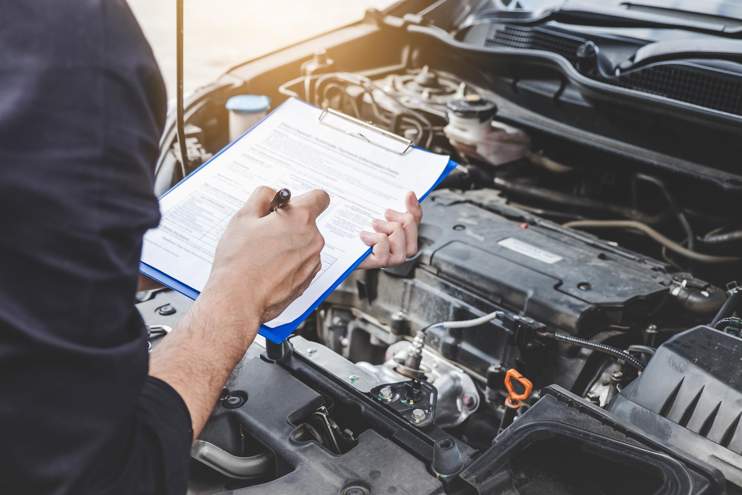Mechanic inspecting engine holding a clipboard