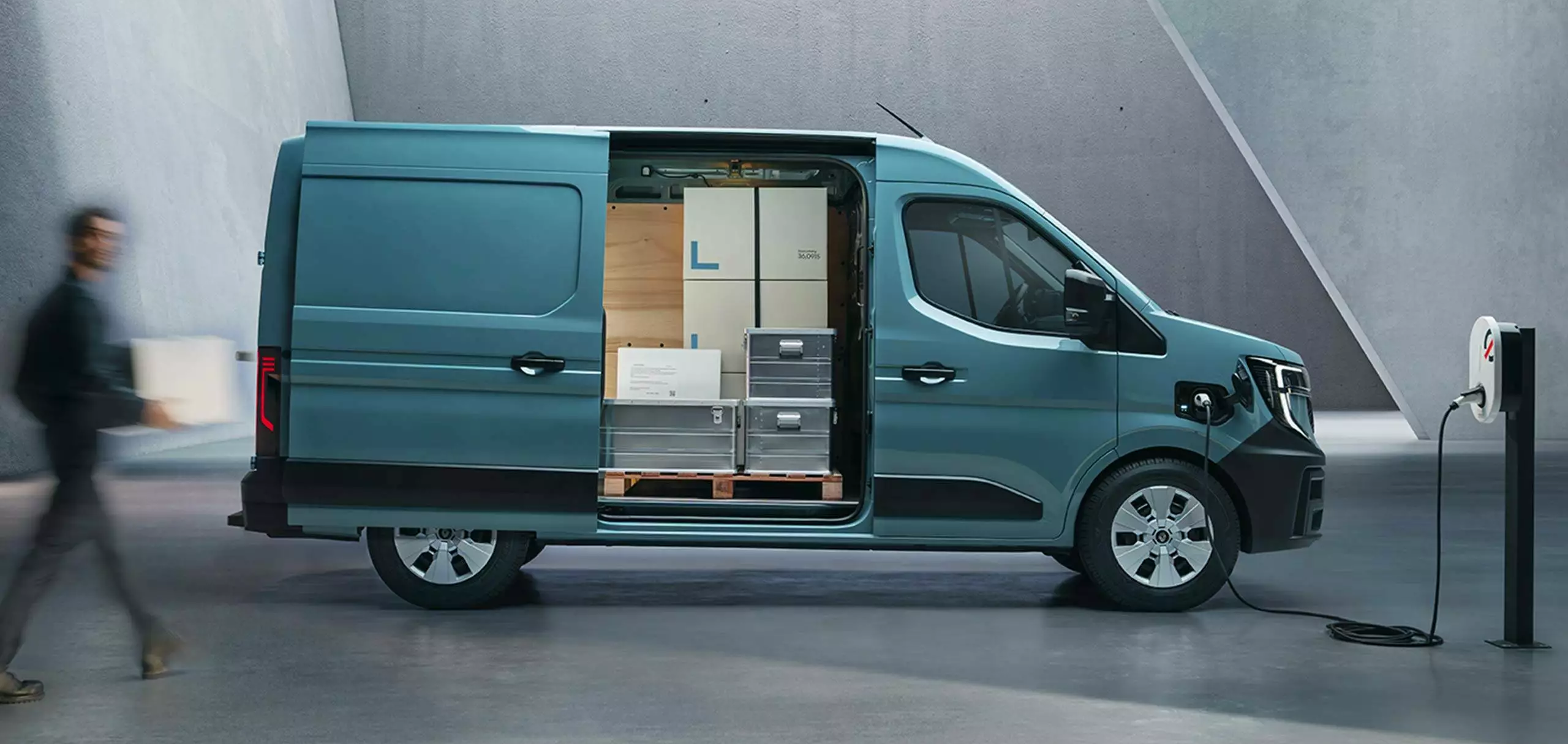 Side view of Renault Master van charging with sliding door open, showing organised cargo area with boxes and equipment.