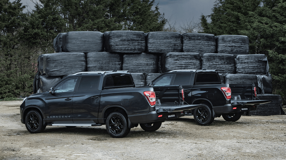 Two black KGM Musso with open tailgates