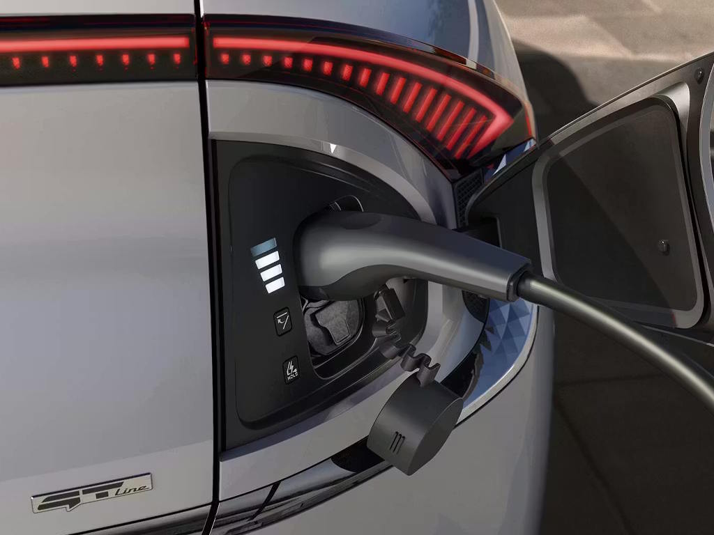 Close-up of the Kia EV6 GT-Line charging port with connector plugged in, showing LED charge indicator lights and distinctive full-width rear light bar above.