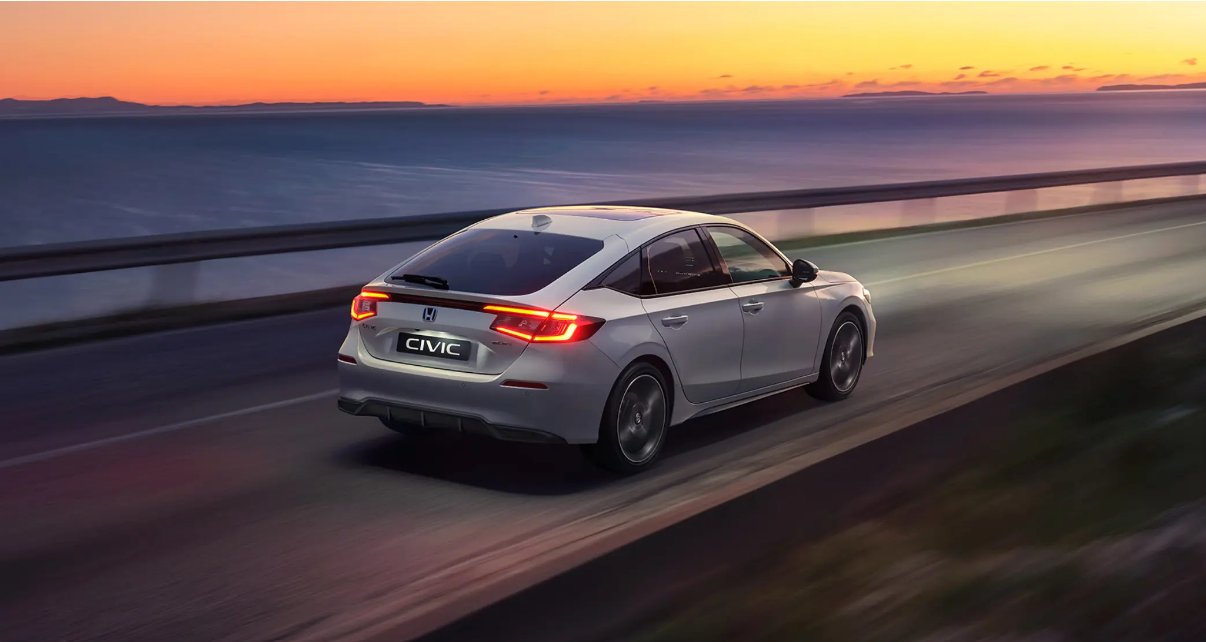 Honda Civic driving along a road into the sunset.