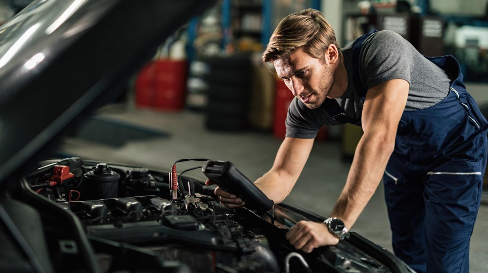 mechanic checking car battery with diagnostic tool