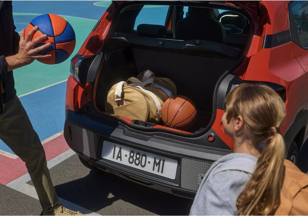 Dacia Spring open boot with sports gear including basketballs and a bag, showing practical storage for everyday use.