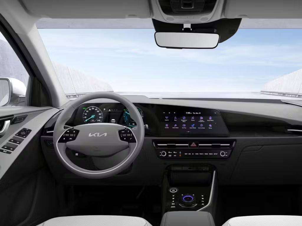 Interior dashboard view of the Kia Niro, featuring the curved dual-screen display, two-tone grey and white upholstery, illuminated rotary gear selector and panoramic sunroof.