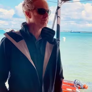 Outdoor portrait of a person by the waterfront with boats and sea views in the background.