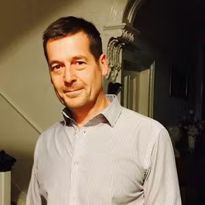 Indoor portrait of a person standing in a home setting with warm lighting.