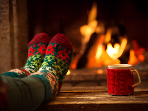 Warm drink and cosy socks by a fireplace during winter.