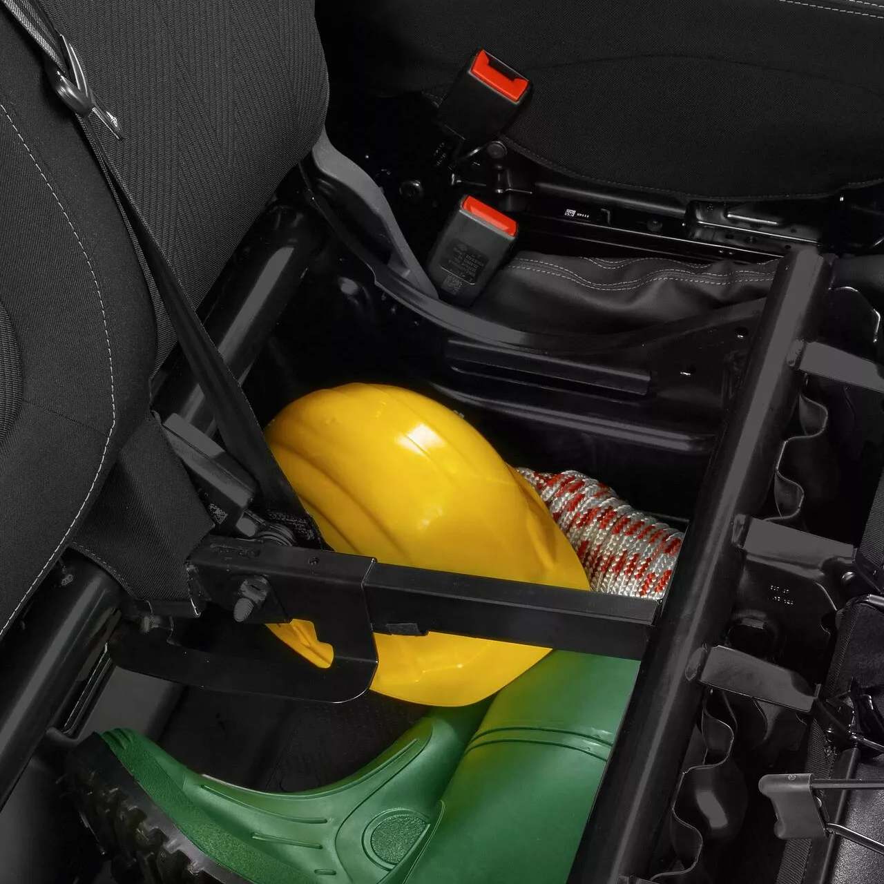 Under-seat storage area of Renault Trafic showing helmet, boots and rope stored beneath the seat.
