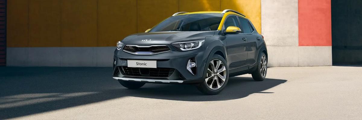 Charcoal grey Kia Stonic parked in front of a yellow, cream and orange wall.