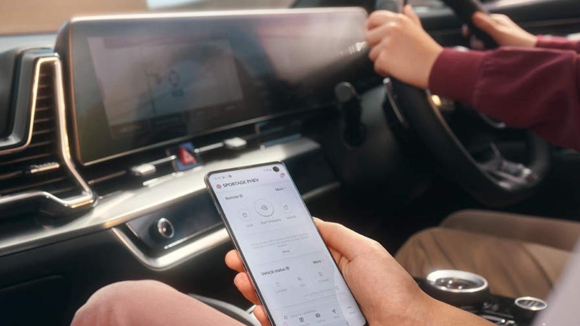 Driver using a smartphone vehicle app inside a modern car, showcasing connected services and remote vehicle management.
