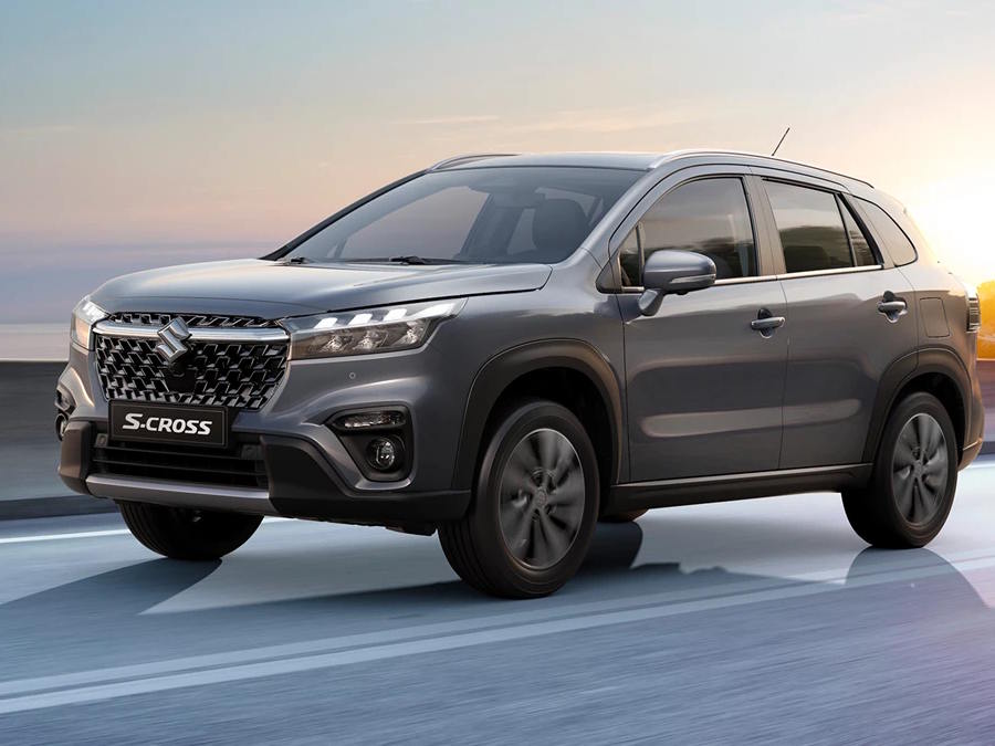 Front three-quarter view of the Suzuki S-Cross compact SUV in metallic grey, featuring a bold chrome-accented grille, sharp LED headlights and rugged body cladding.