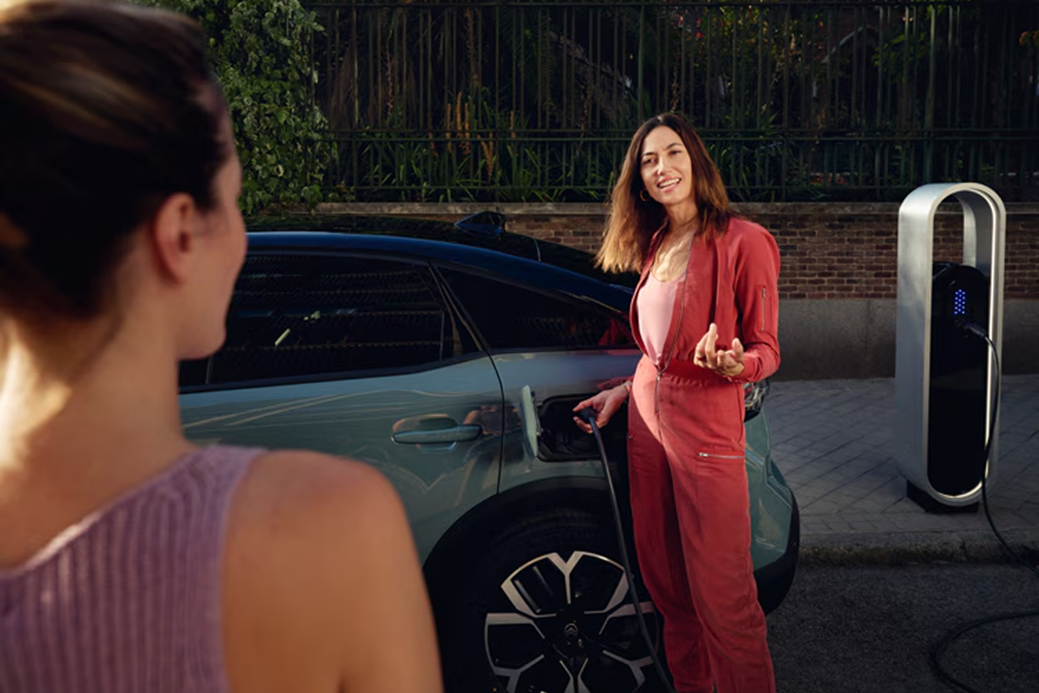 woman talking to her friend whilst plugging in a car charger into her ë-C4